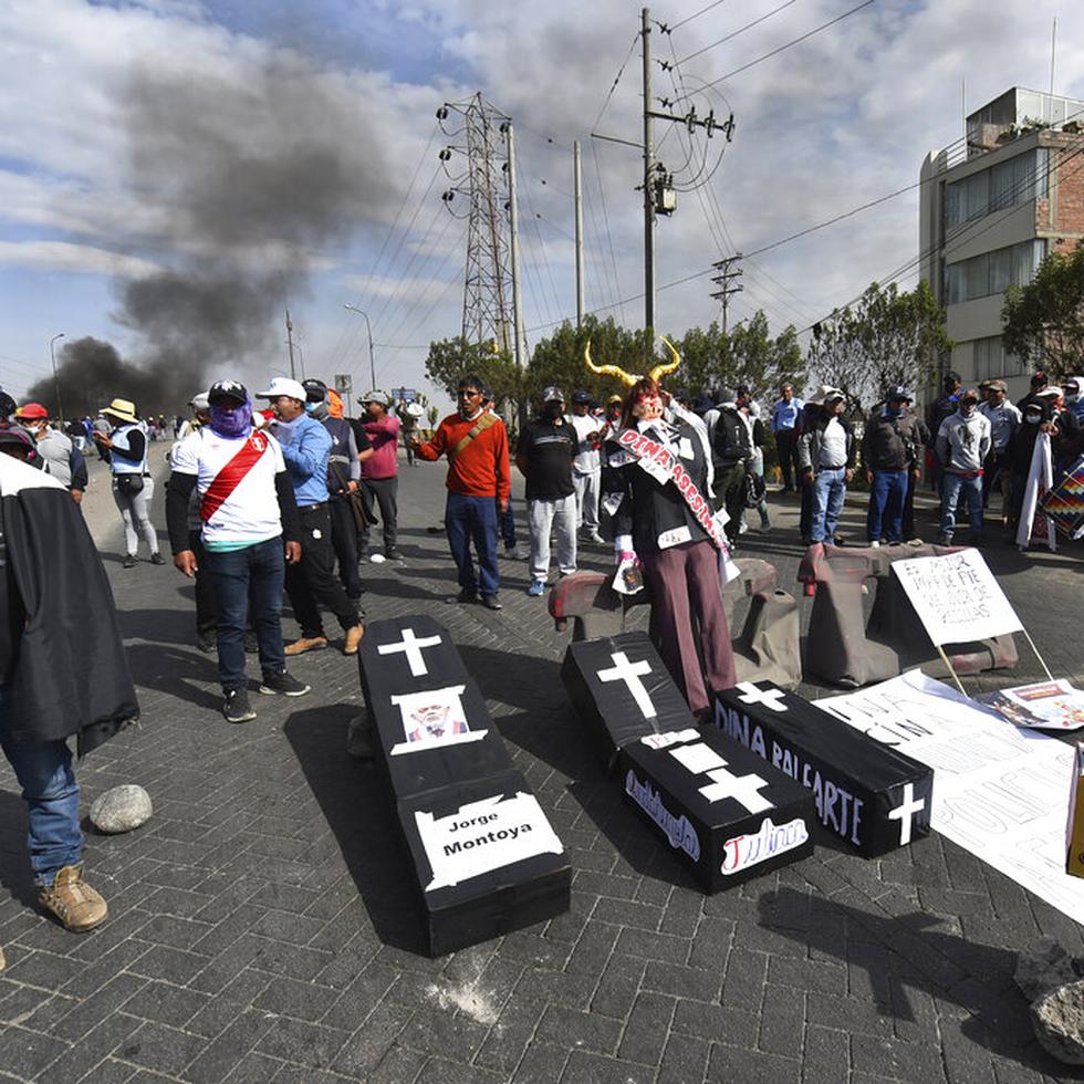 Manifestantes bloquean una carretera con réplicas de ataúdes que llevan los nombres de la presidenta peruana Dina Boluarte y congresistas en Arequipa, Perú, el jueves 19 de enero de 2023. (AP Foto/José Sotomayor)