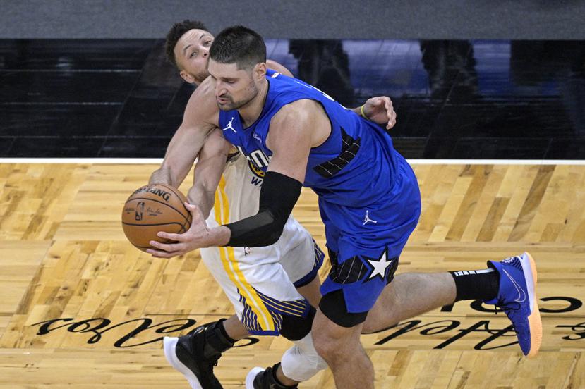 Nikola Vucevic, del Magic de Orlando, recibe una falta de Stephen Curry, de los Warriors de Golden State, en el partido del viernes 19 de febrero de 2021.