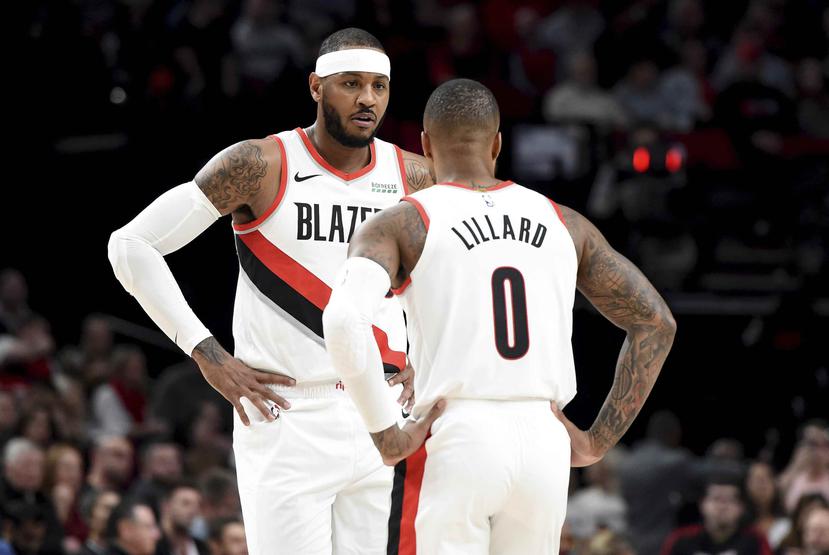 Carmelo Anthony (izquierda), de los Trail Blazers de Portland, habla con su compañero Damian Lillard durante un tiempo muerto en la primera mitad del juego de la NBA. (AP)
