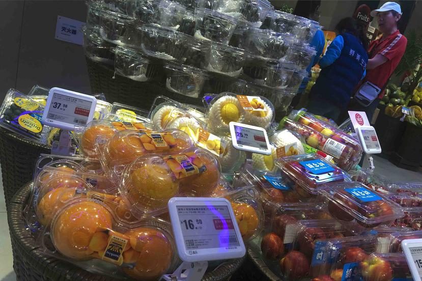 Un hombe charla con trabajadores cerca de una sección con fruta donde se ven naranjas de Estados Unidos y frutas de China en un supermercado de Beijing. (AP)