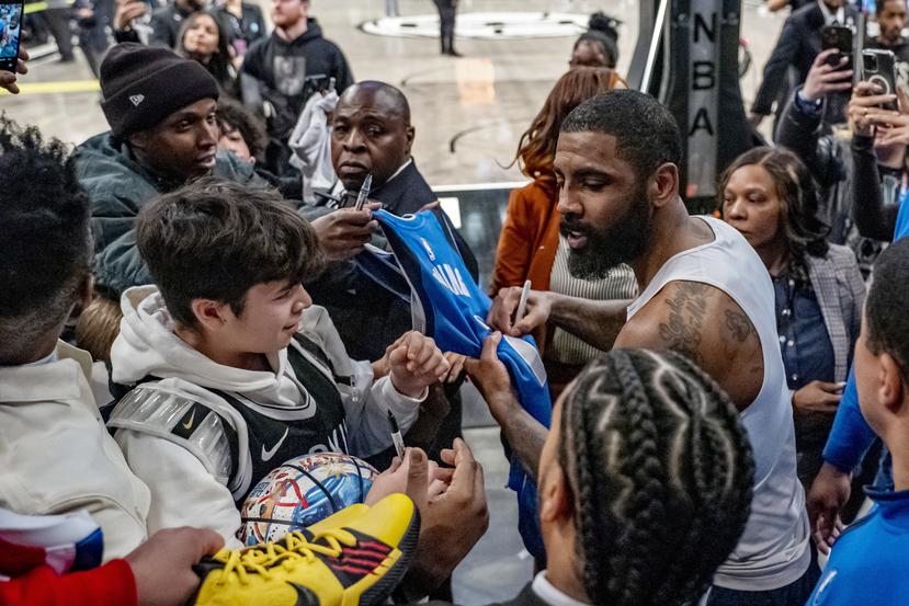 Kyrie Irving le da su autógrafo a varios aficionados luego del partido entre sus Mavericks de Dallas y los locales Nets de Brooklyn.