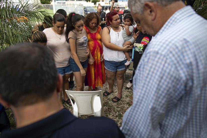 El presidente del Senado Thomas Rivera Schatz (extrema derecha) participa en un círculo de oración con varias familias refugiadas en Guánica.