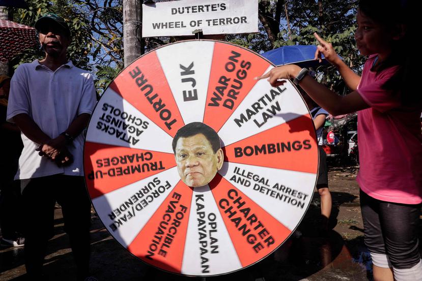 Una mujer da vueltas a una "ruleta del terror" con una imagen del presidente filipino, Rodrigo Duterte, en una manifestación para conmemorar el Día Internacional de la Mujer en Manila, Filipinas (EFE/ Mark R. Cristino).