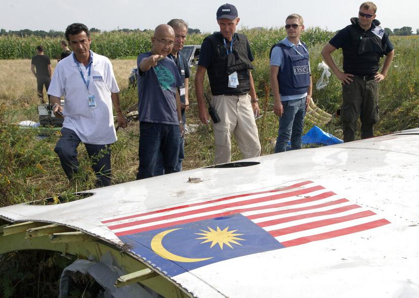 Un equipo de investigadores observa parte del fuselaje del vuelo MH17 de Malaysia Airlines, que volaba entre Amsterdam y Kuala Lumpur. (AP)