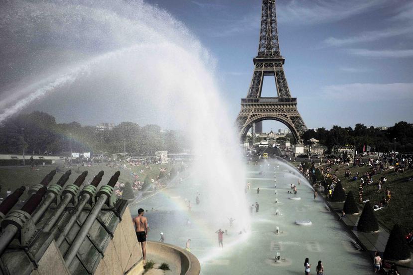 Unas personas se refrescan en las fuentes de los Jardines del Trocadero, frente a la Torre Eiffel, en París. (AP/Lewis Joly)