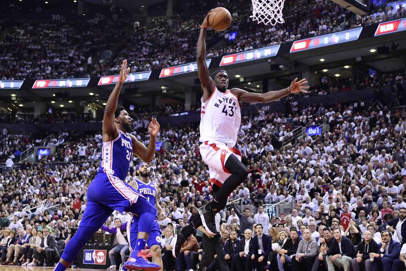 Pascal Siakam, alero de los Raptors de Toronto, salta para realizar un donqueo frente a Joel Embiid, de los 76ers de Filadelfia,. (Frank Gunn/The Canadian Press via AP)