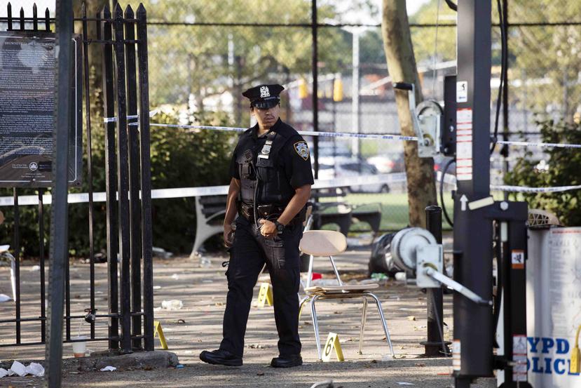 Un policía camina en una calle del vecindario de Brownsville, en Brooklyn, Nueva York, donde la noche anterior hubo un tiroteo, el domingo 28 de julio del 2019. (AP/Mark Lennihan)