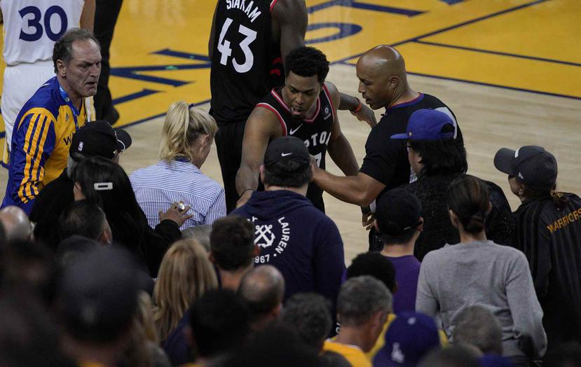 Kyle Lowry se queja con uno de los árbitros luego de ser empujado por el inversionista de los Warriors, Mark Stevens, durante el tercer choque de la serie final de la NBA. (AP / Tony Avelar)