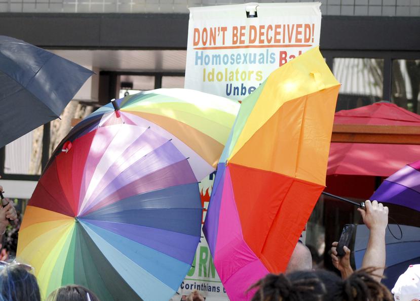 Foto de archivo muestra a un manifestante anti-gay que lleva un cartel que está rodeado por paraguas del Orgullo durante el desfile del Orgullo en Winston-Salem, Carolina del Norte.