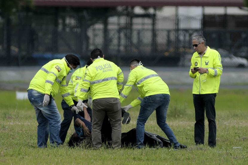 Policías ecuatorianos realizan el levantamiento del cadáver de una de las dos personas que fallecieron al caer presuntamente desde el tren de aterrizaje de un avión en el aeropuerto José Joaquín de Olmedo, en Guayaquil, Ecuador (EFE/Marcos Pin).