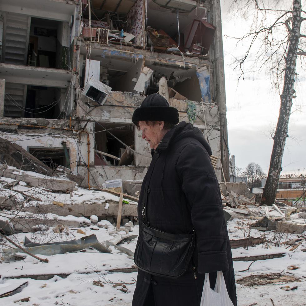 Una mujer pasa frente a un edificio dañado por los bombardeos rusos, el 13 de marzo de 2022, en Kharkiv, Ucrania.