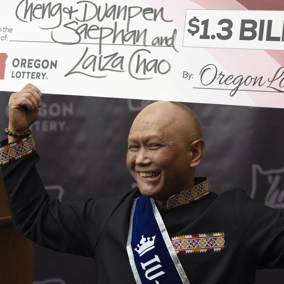 Cheng Saephan levanta un cheque después de hablar en una conferencia de prensa el lunes 29 de abril de 2024 en las oficinas de la Lotería de Oregon, en Salem, Oregon, en la que se reveló que fue uno de los ganadores del premio de 1.300 millones de dólares de la lotería Powerball.