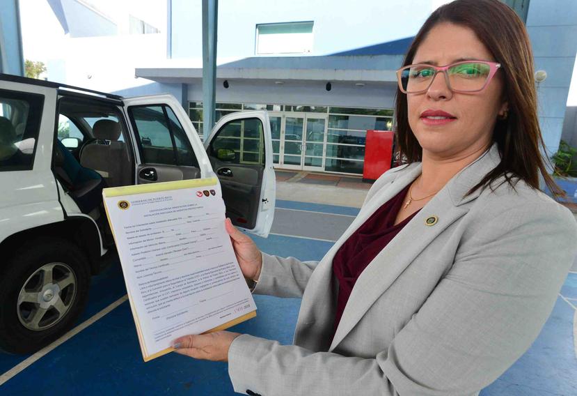 La directora de la Comisión para la Seguridad en el Tránsito, Darelis López Rosario, muestra el certificado que se le entrega a los conductores.