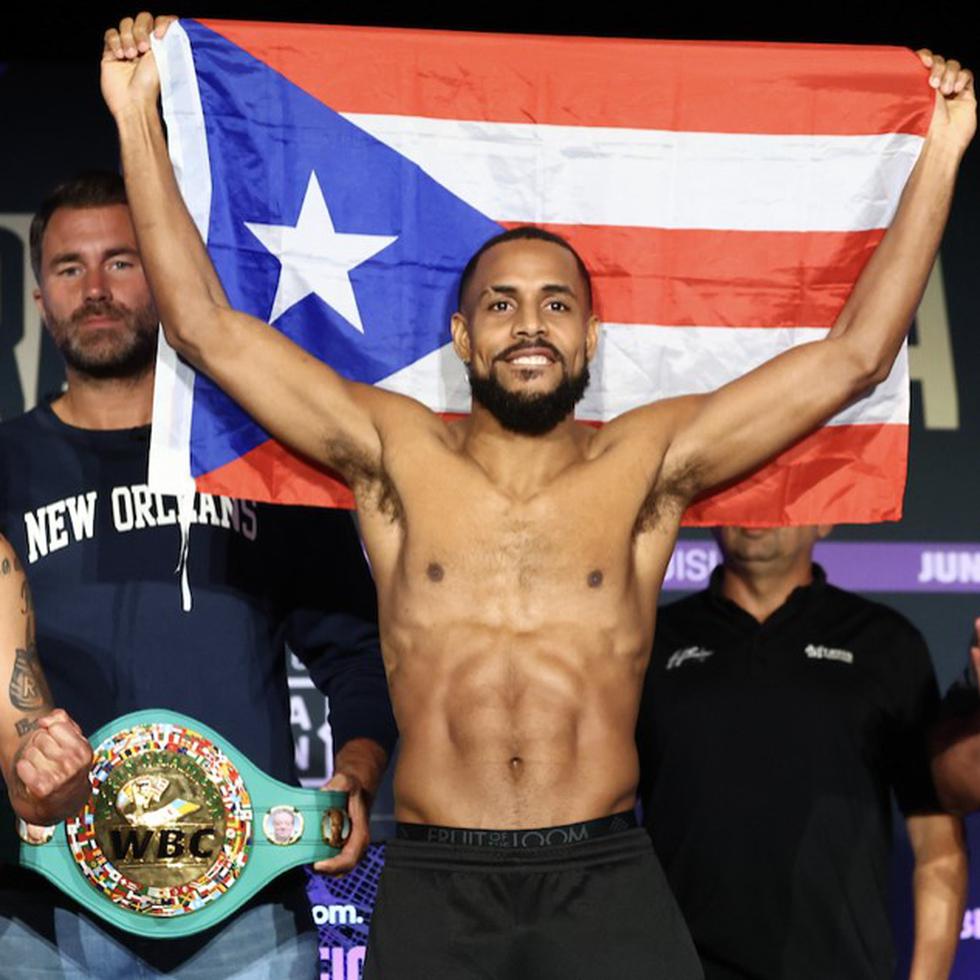 Danielito Zorrilla muestra la bandera de Puerto Rico este viernes durante la ceremonia de pesaje para su pelea de campeonato mundial contra Regis Prograis (izquierda). Al centro, el promotor Eddie Hearn.