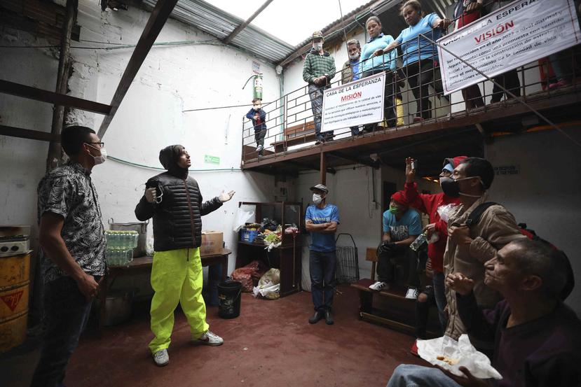 Emiliano Moscoso (segundo desde la izq) conversa con residentes de una casa de un barrio pobre de Bogotá en la que distribuyó hamburguesas gratis. (AP)
