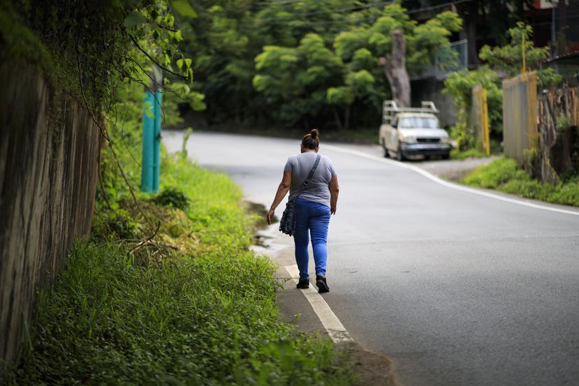 Una mujer camina por una carretera sin acera en la comunidad Monacillos.