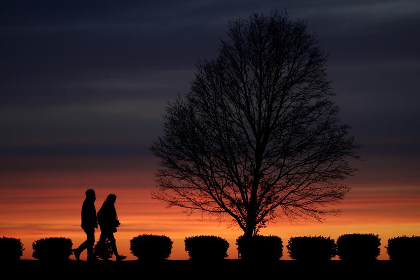 Una pareja camina por un parque en Kansas City, Missouri, a la puesta del sol.