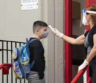 A student has his temperature taken before entering PS 179 elementary school in the Kensington neighborhood, Tuesday, Sept. 29, 2020, in the Brooklyn borough of New York. Hundreds of thousands of elementary school students are heading back to classrooms Tuesday as New York City enters a high-stakes phase of resuming in-person learning during the coronavirus pandemic. (AP Photo/Mark Lennihan)