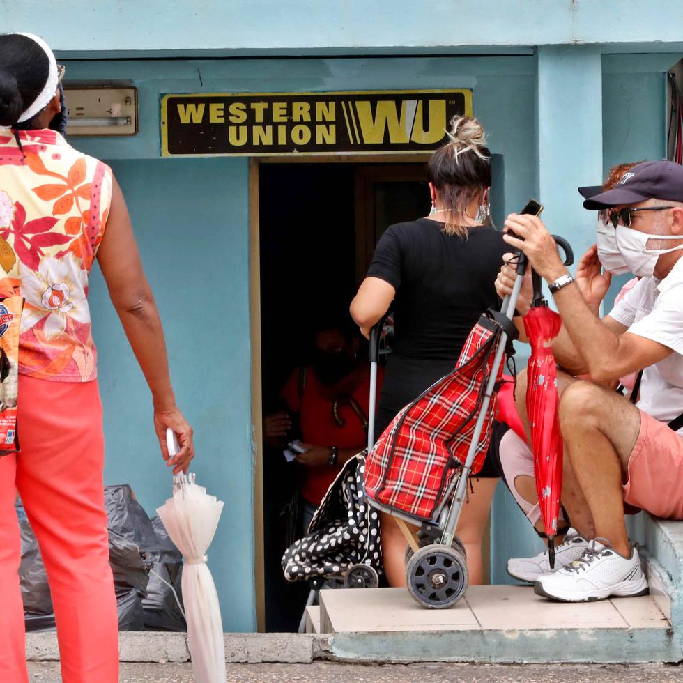 Varias personas esperan fuera de una oficina de Western Union, este jueves en La Habana, (Cuba). (EFE)
