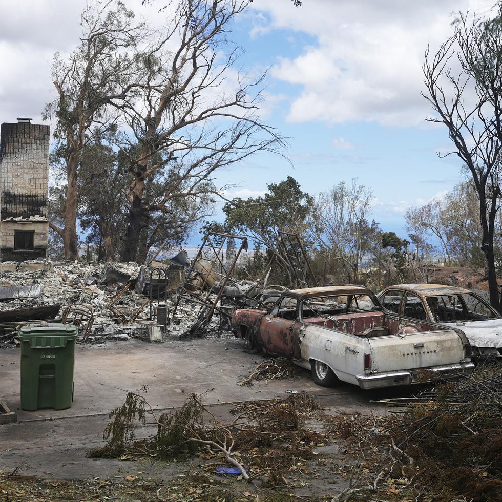 Vehículos calcinados se ven junto a una casa destruida por los incendios el lunes 14 de agosto de 2023, en Kula, Hawai. El mismo día que un incendio devastó la localidad de Lahaina, otro golpeó la población de Kula.