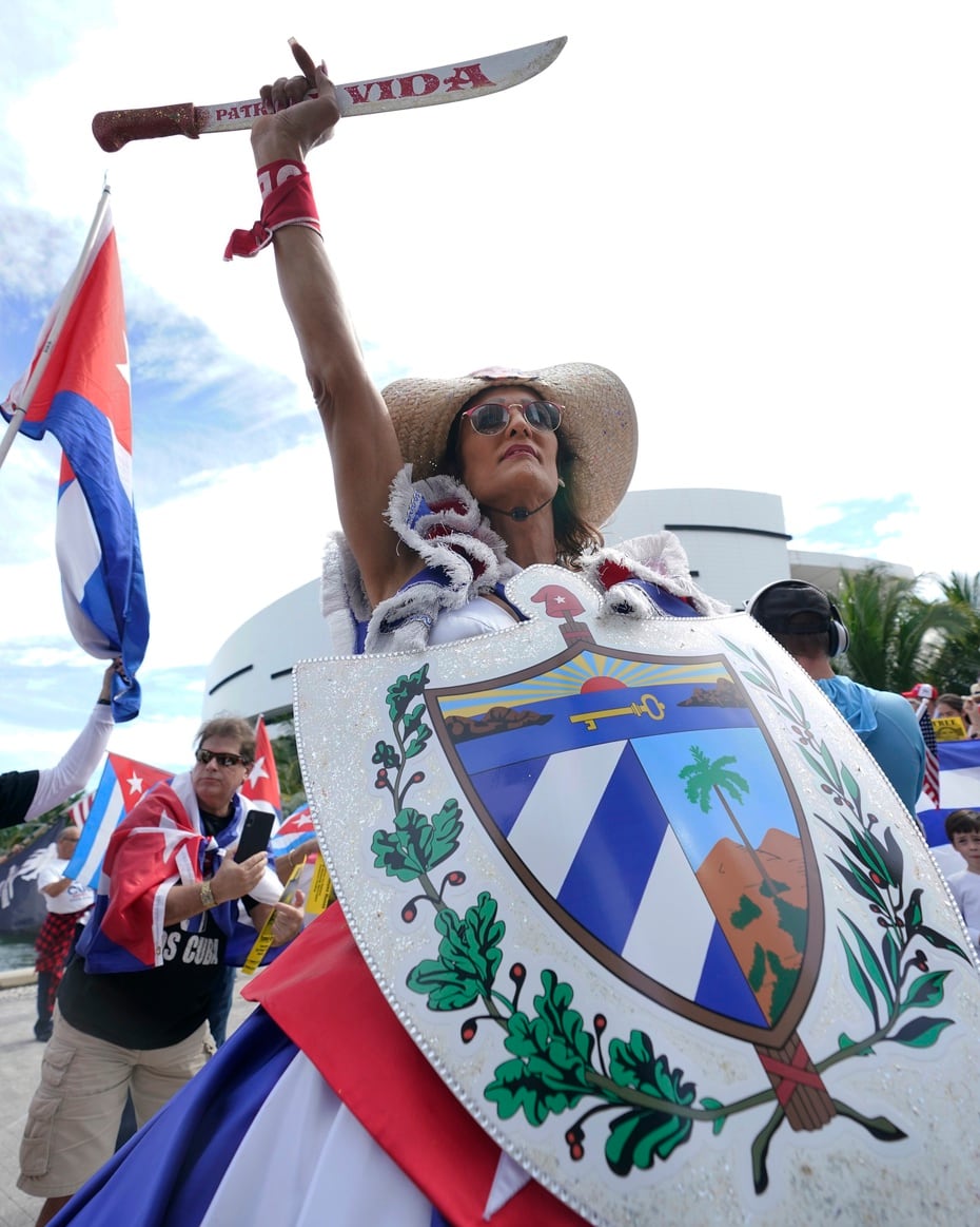 A woman who refused to give her name for fear of reprisals against her family in Cuba, holds a machete while dressed as "The Mambisa", as protesters gather to support protests in Cuba, in downtown Miami.