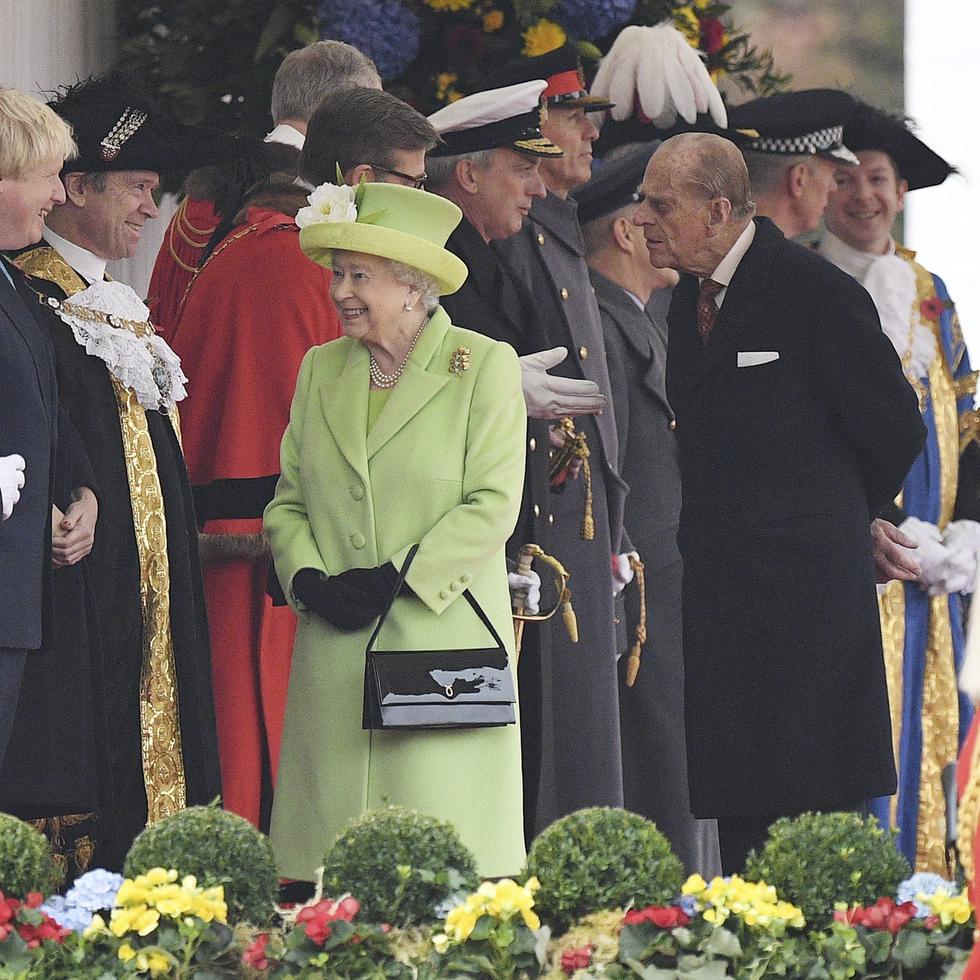 La reina Elizabeth II de Inglaterra  y el duque Felipe de Edimburgo saludan al primer ministro británico (a la izquierda)  Boris Johnson, en un acto en Londres. EFE/FACUNDO ARRIZABALAGA/Archivo