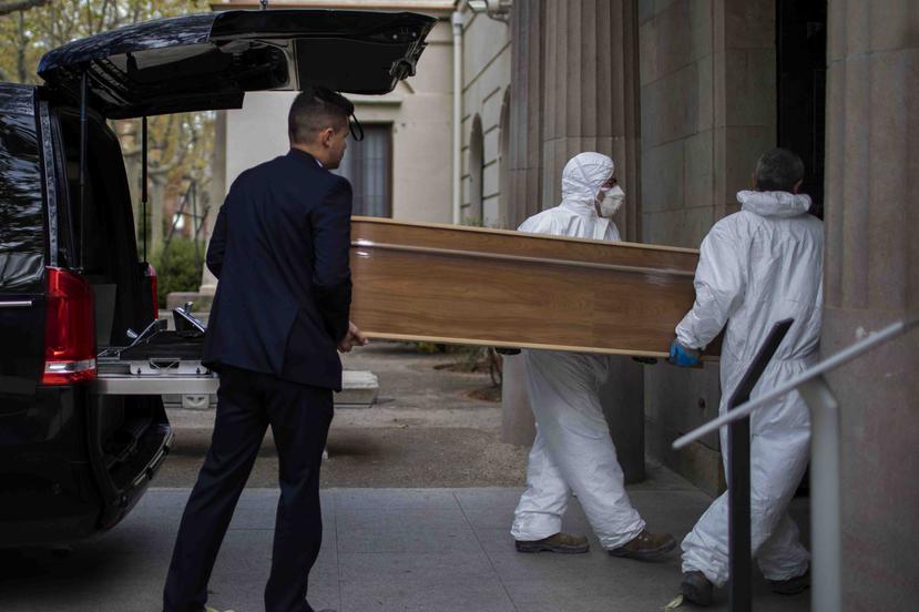 Empleados de una funeraria trasladan un ataúd para un entierro en un cementerio en Barcelona durante el brote del coronavirus. (AP)