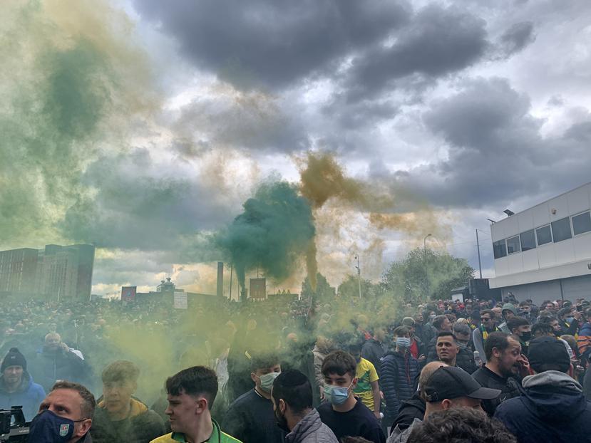 Los fanáticos del Manchester United sostienen bengalas mientras protestan afuera de Old Trafford.
