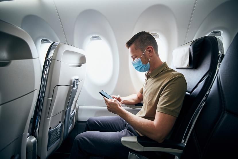 Un hombre utiliza mascarilla mientras está en el interior de un avión.