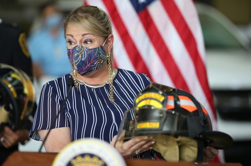 La gobernadora Wanda Vázquez sostiene un casco de un bombero.