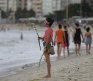 A woman holds flowers at Copacabana beach in Rio de Janeiro, Brazil, Thursday, Dec. 31, 2020. All the accesses to the beaches will be closed on the night of new years, to help curb the spread of COVID-19. (AP Photo/Bruna Prado)