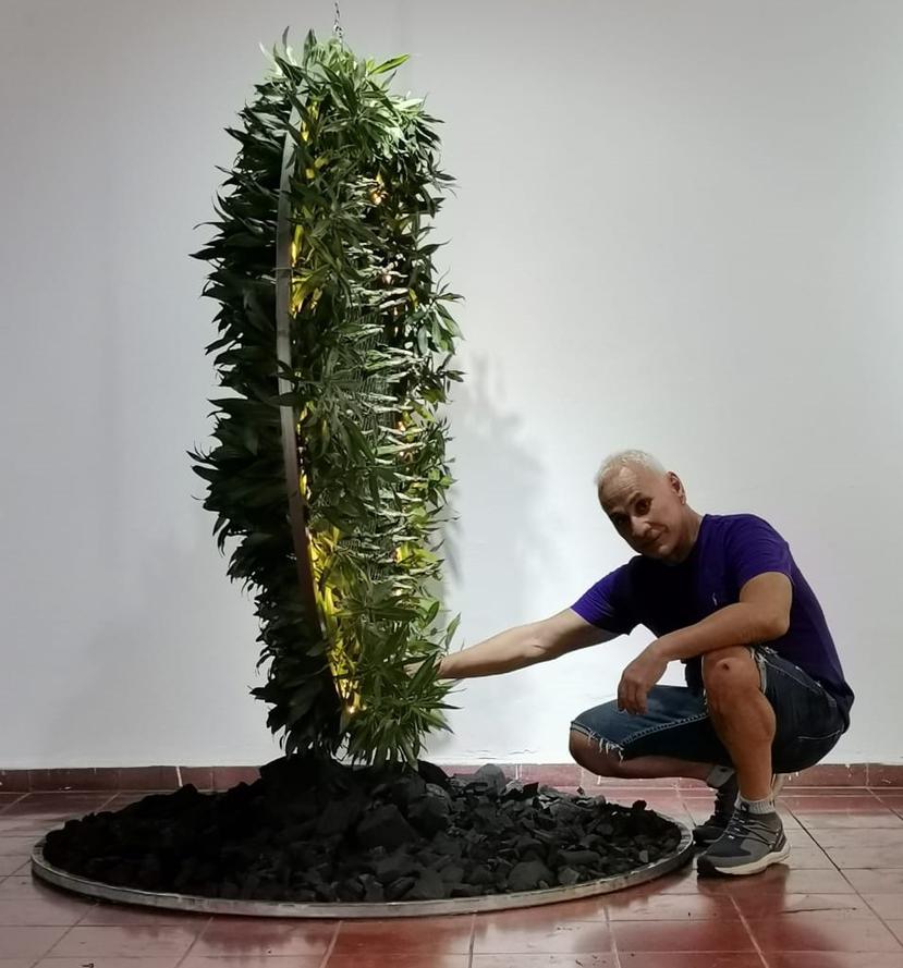 Heriberto Nieves con su pieza Péndulo natural escultura móvil , rota en su centro construida en metal , luz led , vegetación natural y carbón.