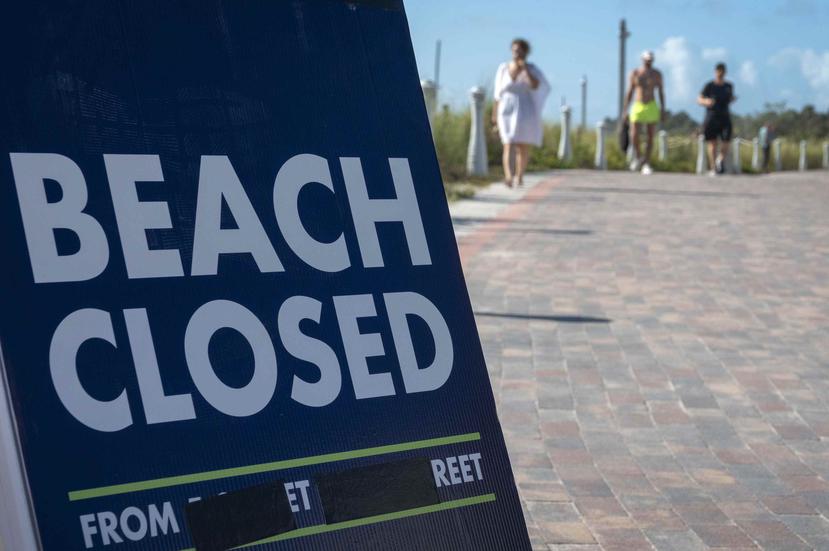 Un cartel alerta a los turistas que la playa está cerrada en South Beach, Florida. (EFE)