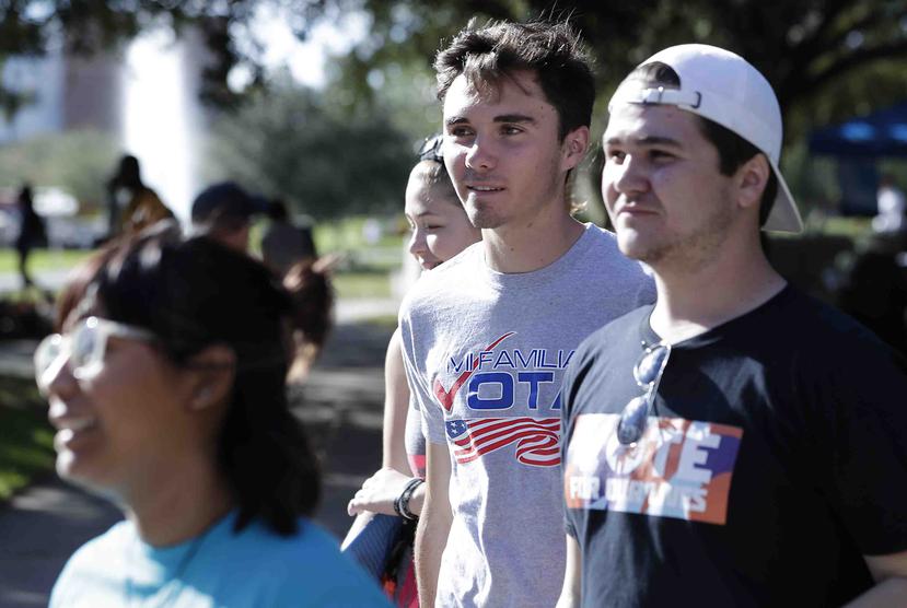David Hogg (al centro), un estudiante sobreviviente de la masacre en la secundaria Stoneman Douglas de Parkland, camina con voluntarios a un sitio de votación anticipada en el campus de la University of Central Florida en Orlando, Florida. (AP)