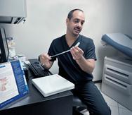 El doctor Omar Soto, especialista en urología, muestra el dispositivo AMS 800 para tratar la incontinencia urinaria por esfuerzo en hombres.