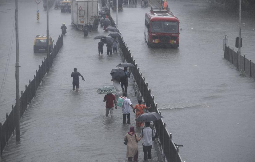 La gente camina por una calle inundada durante las fuertes lluvias en Mumbai, India.