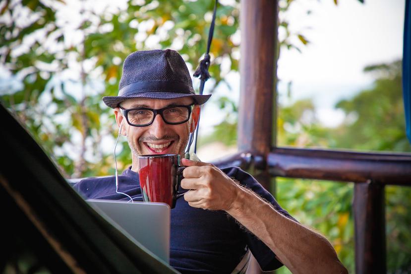 Hombre toma café mientras trabaja desde su balcón.
