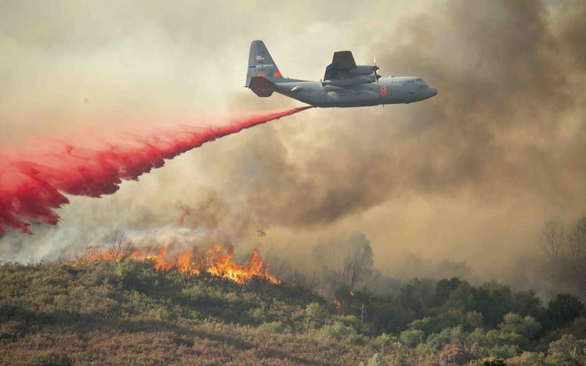 Un avión de la fuerza aérea de Estados Unidos deja caer retardante de fuego sobre una colina en llamas a causa del Incendio Ranch, en Clearlake Oaks, California, el domingo 5 de agosto de 2018. (AP/Josh Edelson)