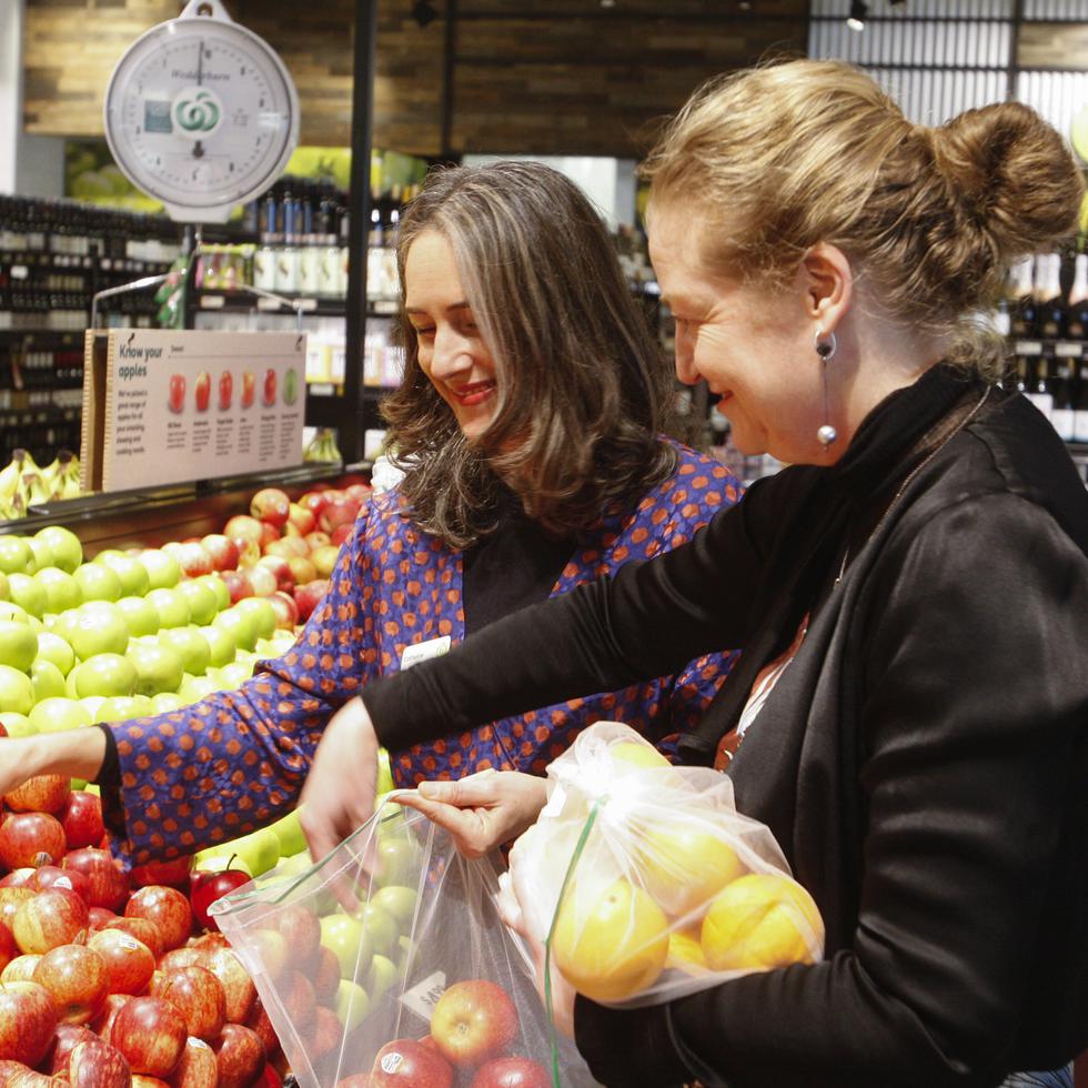 Catherine Langabeer, izquierda, jefa de sostenibilidad de la cadena de supermercado Countdown, y la ministra de Medio Ambiente, Rachel Brooking, muestran cómo utilizar una bolsa de poliester reutilizable, el 29 de junio de 2023, en Wellington, Nueva Zelanda.