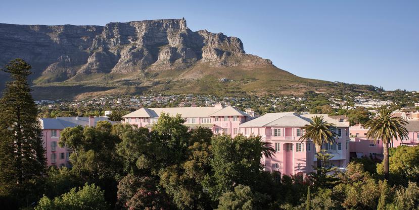 Belmond Mount Nelson Hotel es otro ícono de Ciudad del Cabo, donde puedes disfrutar de su legendario té vespertino. Al fondo, la icónica cima de Table Mountain, unos de los lugares que debes visitar. 