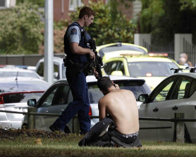 Un hombre descansa en el suelo mientras habla por su teléfono celular del otro lado de la calle de una mezquita en Christchurch, Nueva Zelanda. (AP)