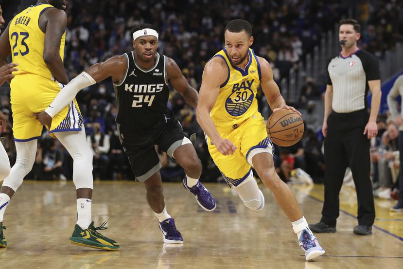 Stephen Curry (30), de los Warriors de Golden State, esquiva a Buddy Hield (24) de los Kings de Sacramento en el partido de la NBA en San Francisco, el 20 de diciembre de 2021. Golden State venció 113-98 a Sacramento.