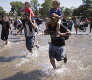 Migrantes centroamericanos corren cargando niños en sus hombros a través del río Suchiate desde Guatemala y cerca de Ciudad Hidalgo, México, el lunes 20 de enero de 2020, con la esperanza de convencer a las autoridades mexicanas de que les permitan pasar por el país para seguir con rumbo a Estados Unidos.