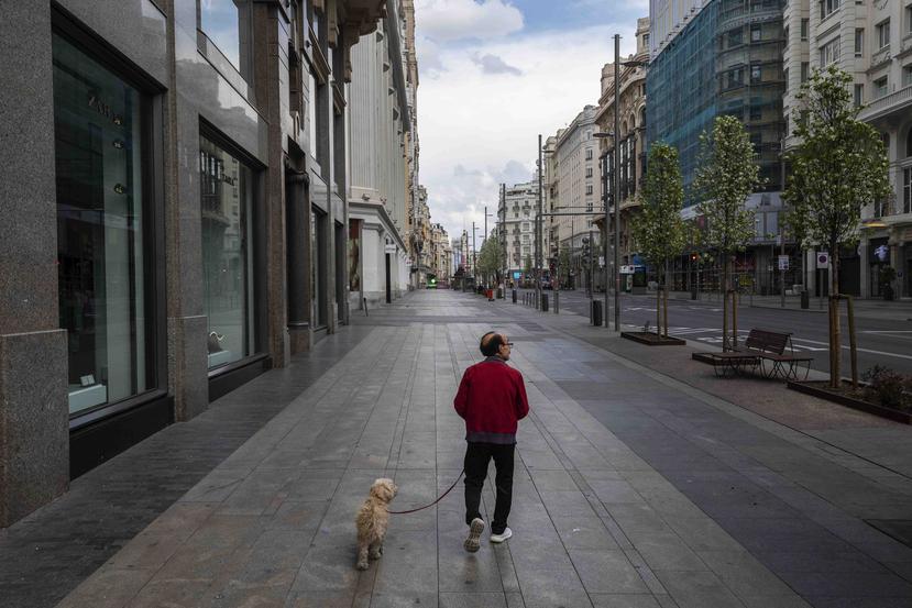 Un hombre pasea a su perro en una de las calles vacías de Madrid por el coronavirus. (AP)