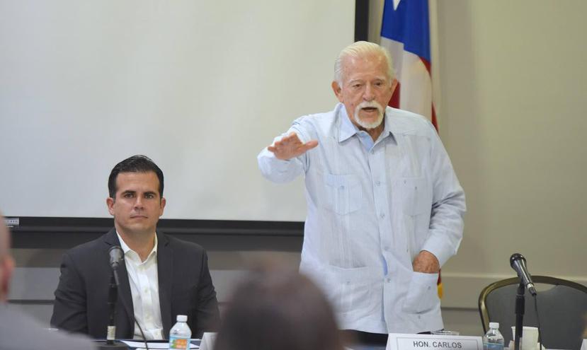 El exgobernador Carlos Romero Barceló (de pie) junto al gobernador Ricardo Rosselló durante una reunión de la Comisión de Igualdad en Miami. (Suministrada)
