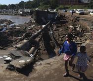 Dos niñas caminan en un camino dañado en Durban, Sudáfrica.