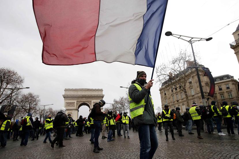 Un manifestante de los "chalecos amarillos" ondea una bandera francesa durante una manifestación en París, Francia. (EFE)