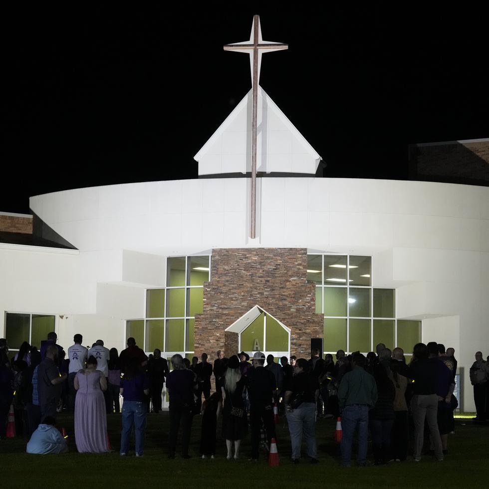 Un grupo de personas se reúnen en el césped con tubos luminosos para despedir a Audrii Cunningham en la First Baptist Church de Livingston, Texas.