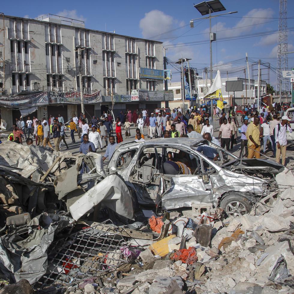 Gente caminando entre la destrucción dejada por dos coches bomba en una transitada intersección en Mogadiscio, Somalia.
