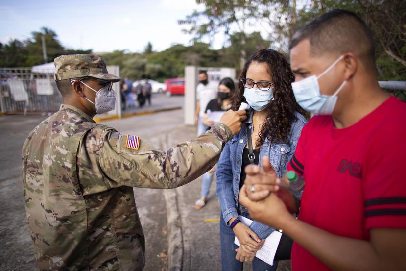 Un soldado toma la temperatura a unos ciudadanos.